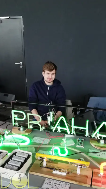 Pohled na stůl s neonovými exponáty, cedulí PRAHA a dalšími výrobky